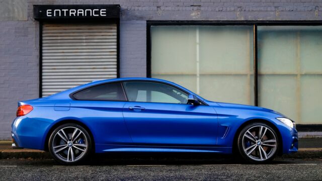 blue coupe beside gray house